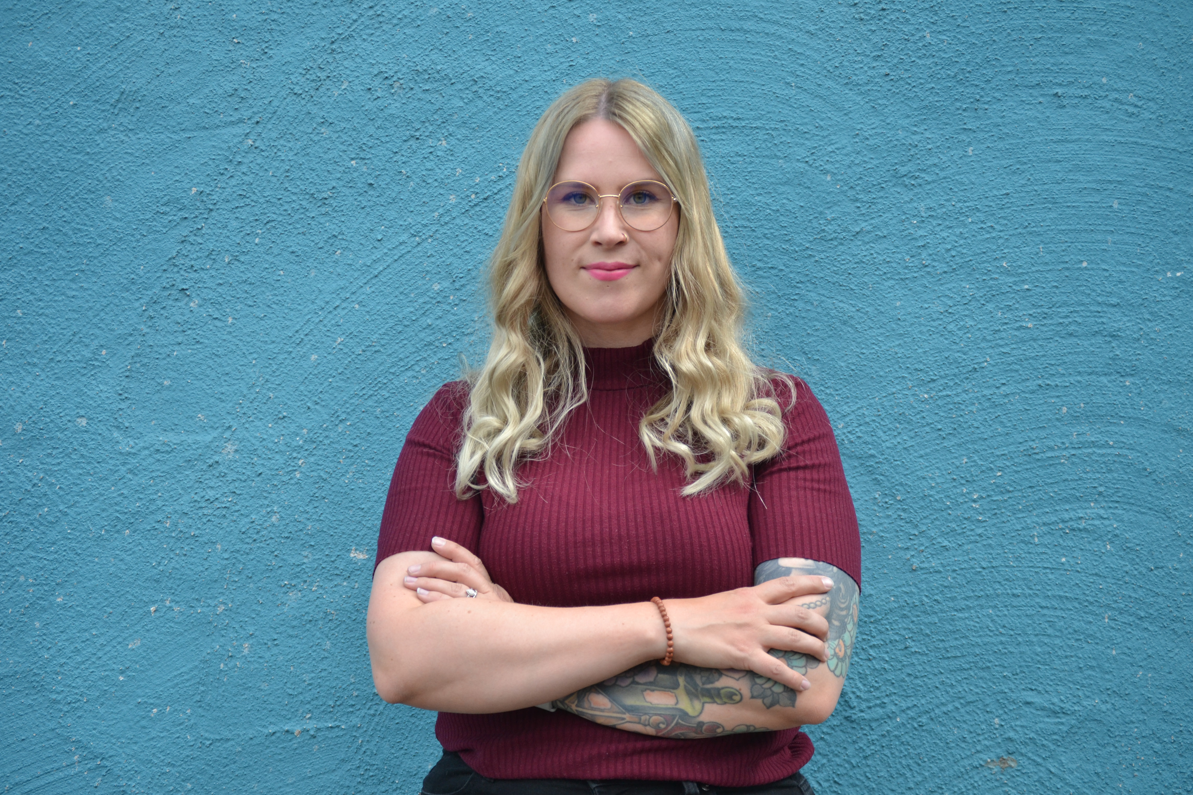 Emma Lindqvist katsoo kameraan kädet puuskassa. Taustalla näkyy Raision kirjaston sininen seinä.